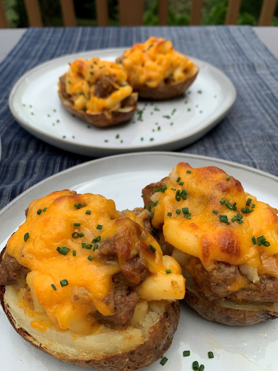 A patio table set with a tablecloth and two plates of potato skins garnished with chives.