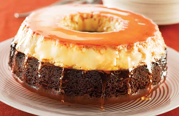 Una rosca de pastel de chocolate cubierto con flan sobre una fuente blanca.