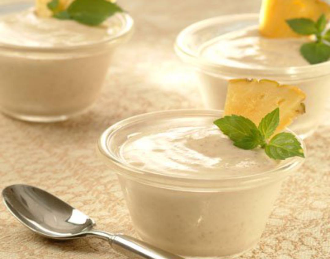 Tazas cremosas de piña y almendras en frascos transparentes con ramitas de menta.