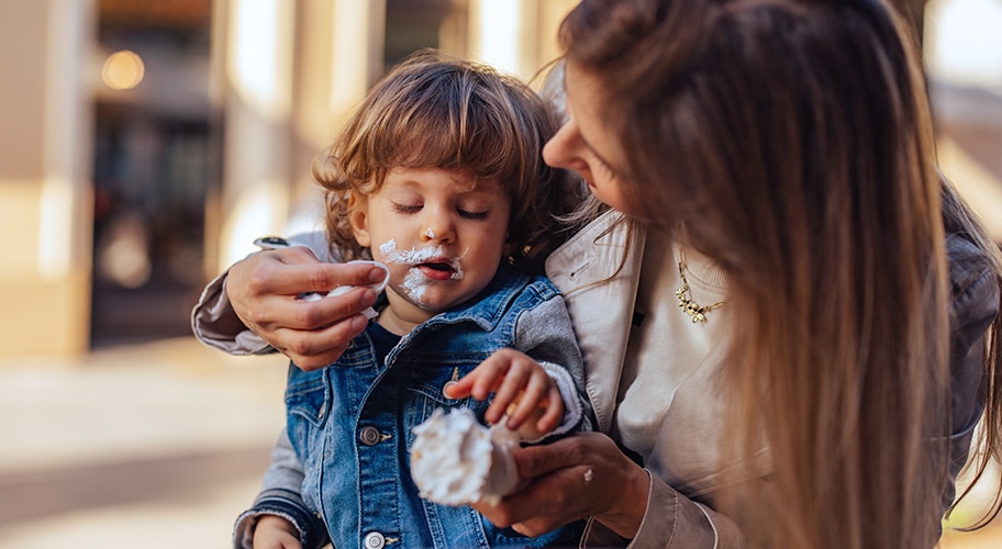 Una madre limpia restos de helado de la cara de un niño.