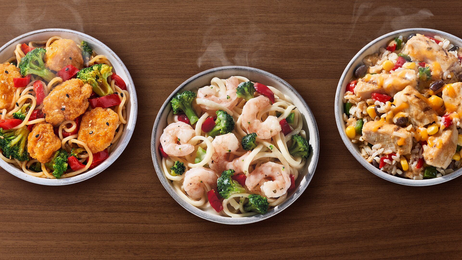 Bowls of Lean Cuisine Shrimp Alfredo, Savory Sesame Chicken & Vegetables, and Unwrapped Chicken Burrito on a wooden table.