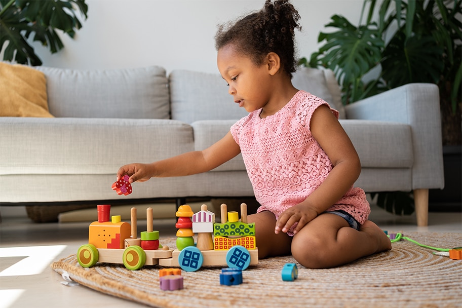 Un niño pequeño juega con bloques en el suelo frente a un sofá.