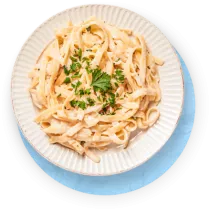 Close up of pasta on a white plate against a blue background.
